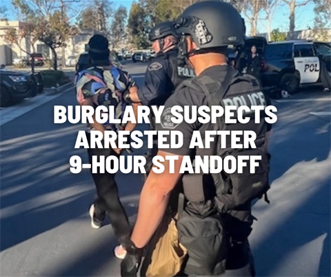 Burglary suspect being escorted by two police officers to a patrol car