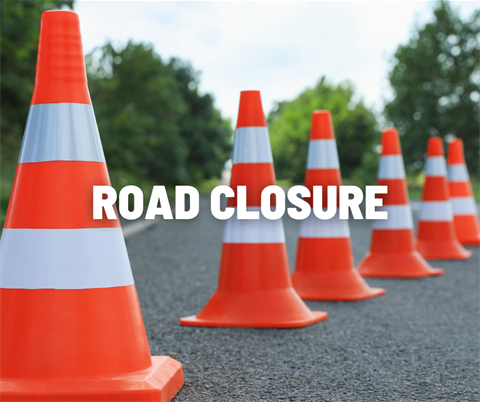 the words road closure in the background are traffic cones on an empty road